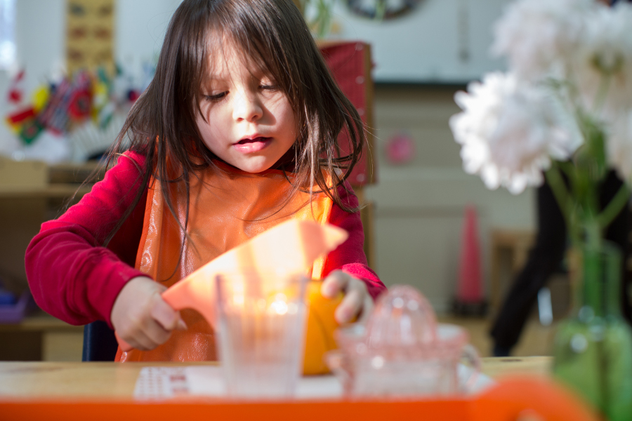 Child squeezing an orange in a practical life lesson